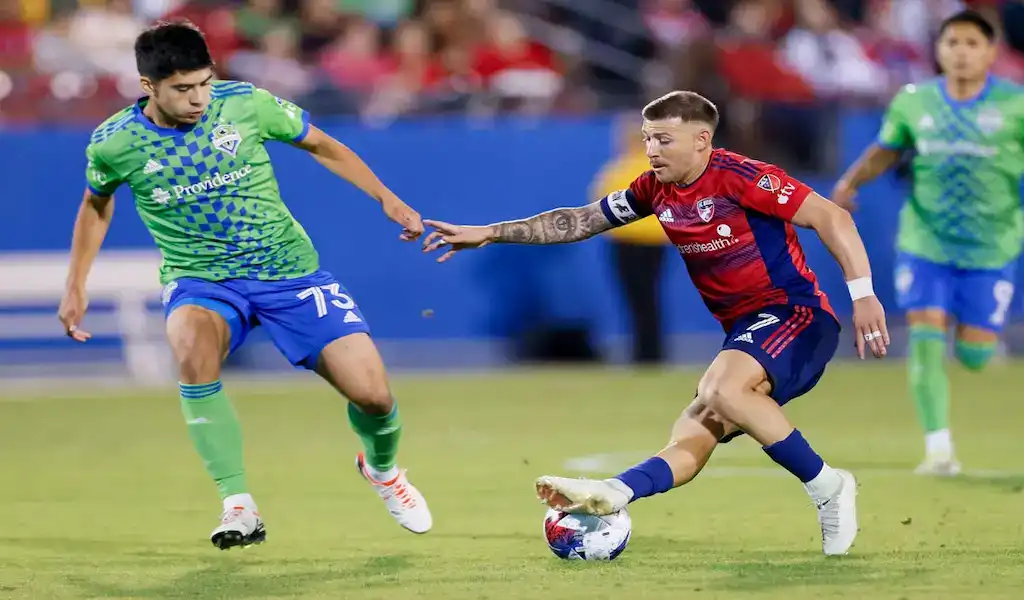FC Dallas player controls the ball while pressured by a Seattle Sounders FC defender during an MLS match.