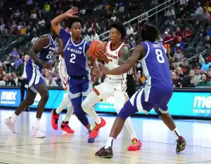 USC Trojans player drives through Kansas State defenders during a college basketball game