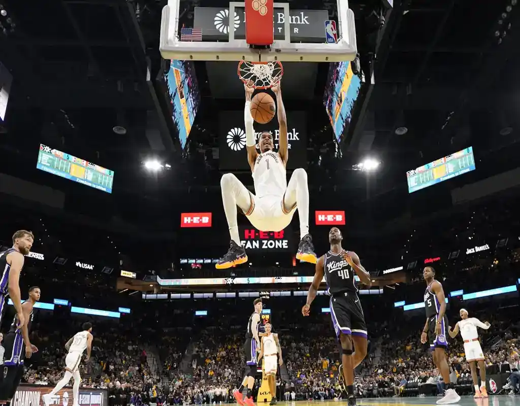 San Antonio Spurs player dunks during game against Sacramento Kings with teammates and crowd watching