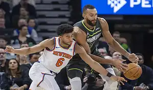 Minnesota Timberwolves player battles for possession of the ball against a New York Knicks defender during an NBA game.
