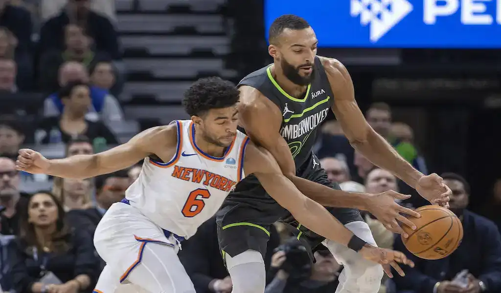Minnesota Timberwolves player battles for possession of the ball against a New York Knicks defender during an NBA game.