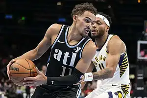 Atlanta Hawks player dribbling the basketball while being tightly defended by an Indiana Pacers player.