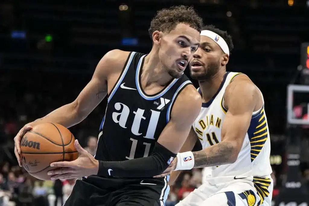 Atlanta Hawks player dribbling the basketball while being tightly defended by an Indiana Pacers player.