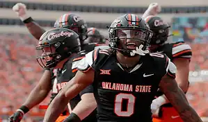Oklahoma State Cowboys football players celebrate after a big play against the UCF Knights during a college football game.
