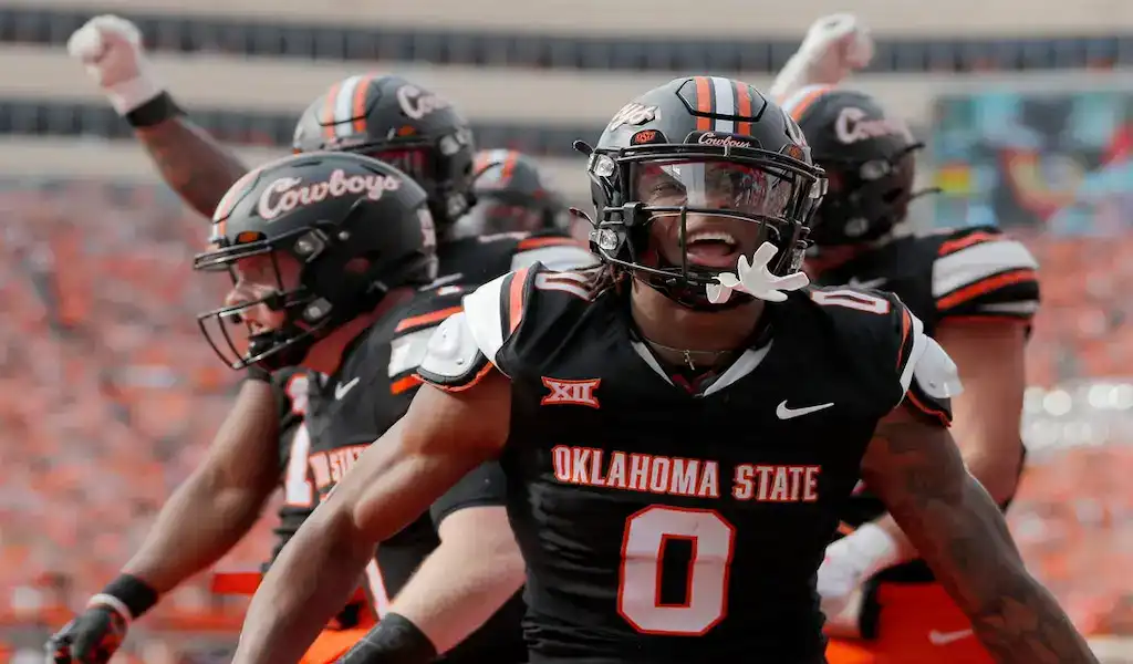 Oklahoma State Cowboys football players celebrate after a big play against the UCF Knights during a college football game.