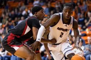A UTEP Miners basketball player drives past a defender in black and red.