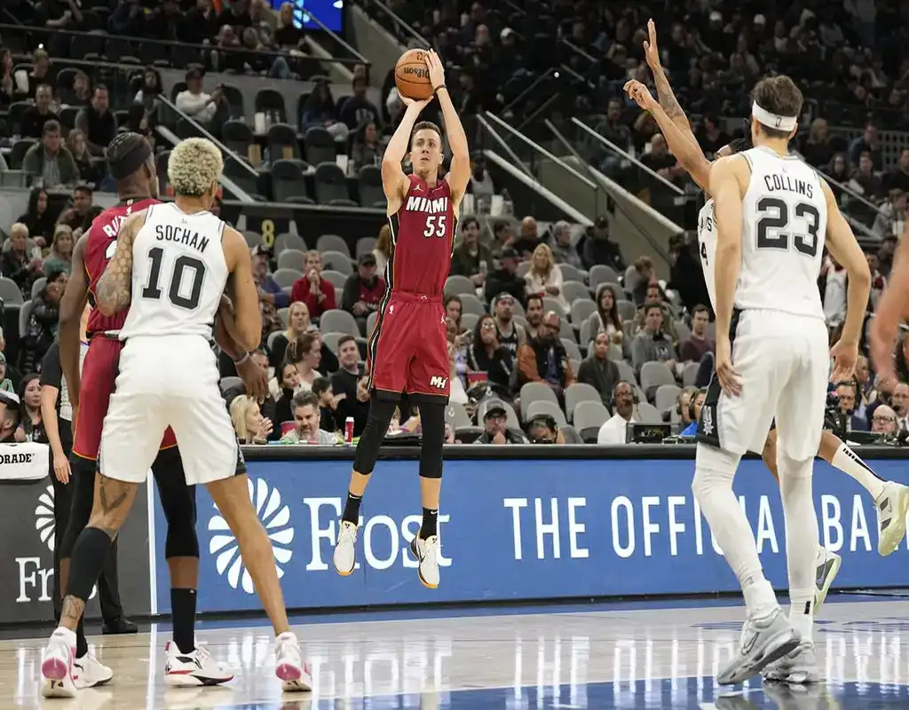 Miami Heat player #55 rising for a jump shot as Charlotte Hornets defenders close in during an NBA game.