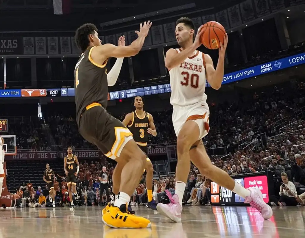 Texas Longhorns player drives toward the basket while defended by a Texas State Bobcats player during their game on November 30, 2023.
