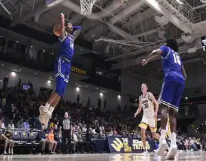 Seton Hall Pirates player #14 jumping for a dunk over a Northeastern Huskies defender under the basket