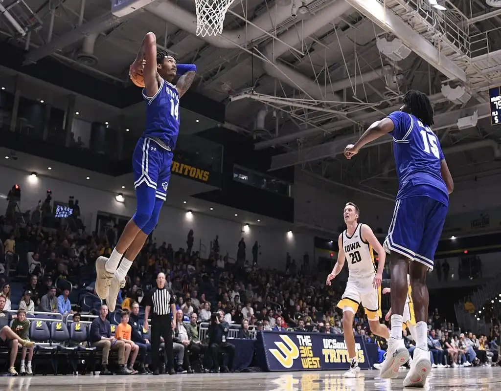 Seton Hall Pirates player #14 jumping for a dunk over a Northeastern Huskies defender under the basket