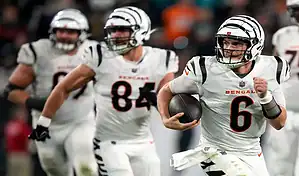 Cincinnati Bengals quarterback runs the ball with teammates blocking during an NFL game against the Colts.