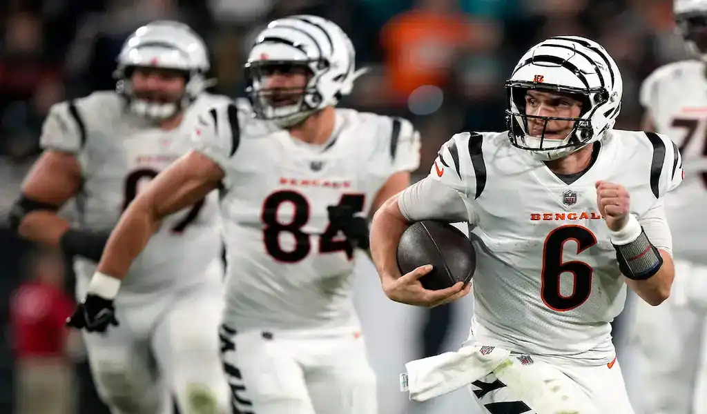 Cincinnati Bengals quarterback runs the ball with teammates blocking during an NFL game against the Colts.