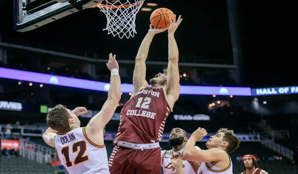 Boston College Eagles player dunks over NC State Wolfpack defenders during NCAA basketball game on December 2, 2023.