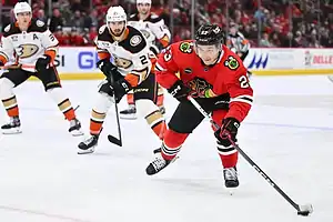 Chicago Blackhawks player skates with the puck as Anaheim Ducks defenders close in.