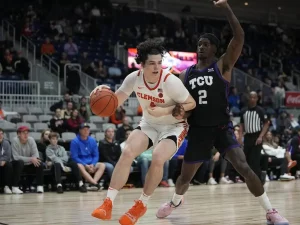 A Clemson basketball player drives toward the basket while being closely guarded by a TCU defender.
