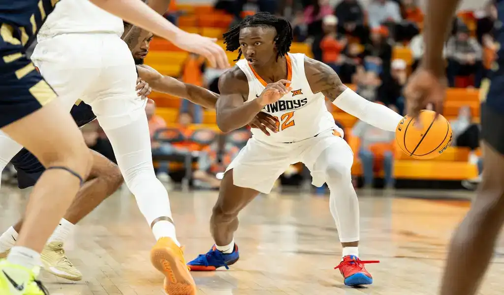 Oklahoma State Cowboys player dribbling the basketball while being defended during a college basketball game.