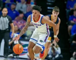 A Florida Gators basketball player chases down a loose ball while being closely pursued by a defender.