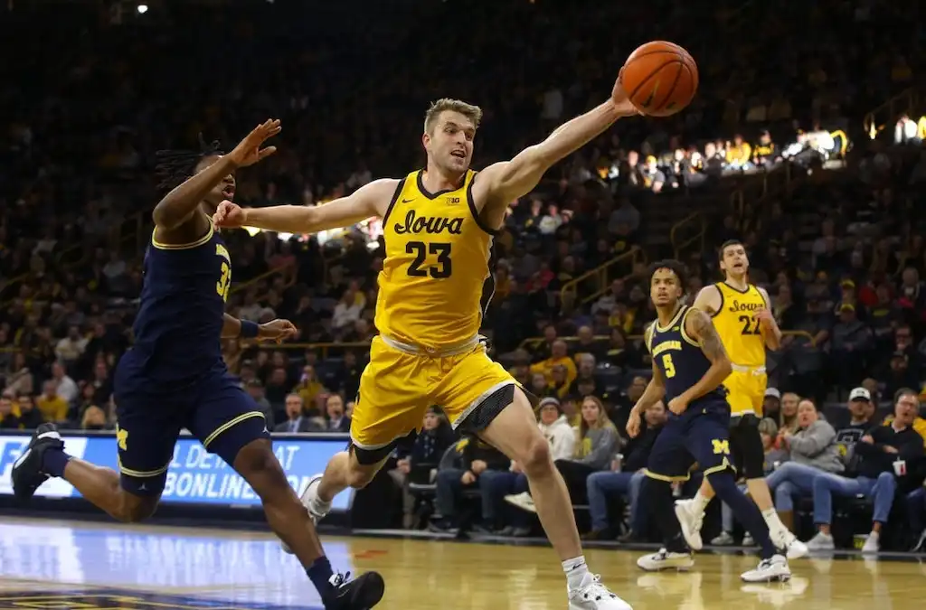 NCAAB 1 An Iowa basketball player stretches out to save the ball from going out of bounds.