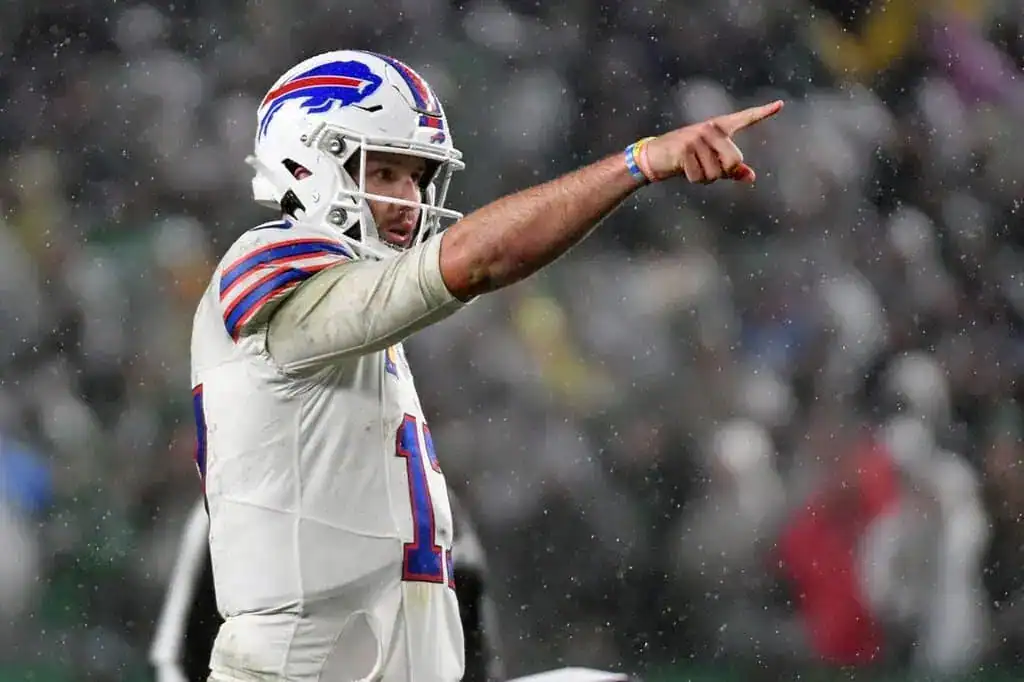 Buffalo Bills quarterback Josh Allen in the rain pointing and calling a play during an NFL game.