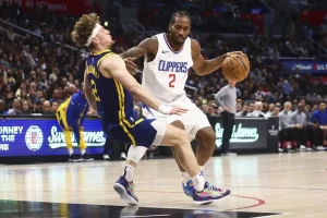 LA Clippers player drives to the basket with the ball as a Golden State Warriors defender falls.