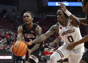 New Mexico State basketball player battles for possession of the ball with a Louisville player.