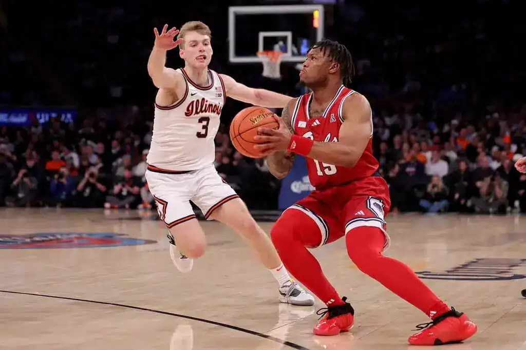 Ole Miss basketball player driving to the basket against an Illinois defender in a college basketball game.