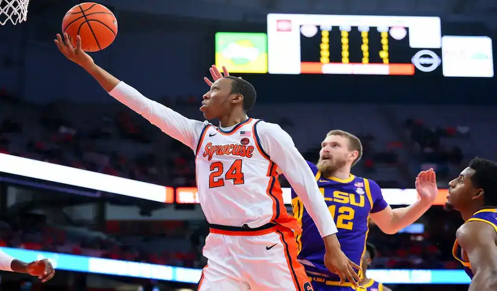 Syracuse Orange player going up for a layup against LSU defenders during a college basketball game.