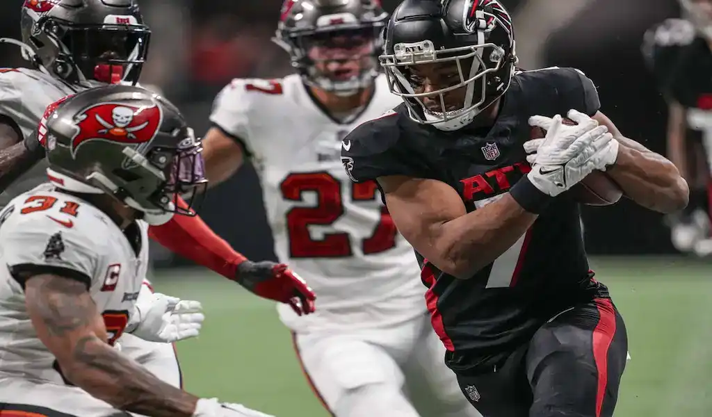 Atlanta Falcons player runs the ball against the Tampa Bay Buccaneers defense during an NFL game.