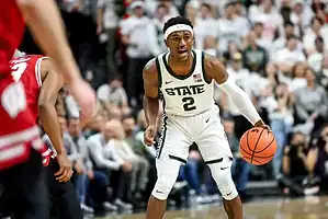 Two Vancouver Canucks hockey players in white jerseys stand close together on the ice during a game, appearing to talk strategy.