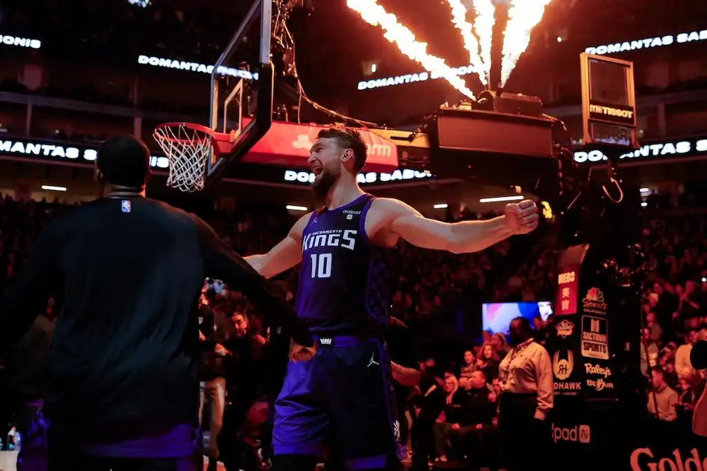 A Sacramento Kings player celebrates on the court with flames shooting overhead.