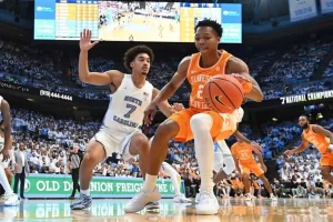Basketball game between Tennessee Volunteers and North Carolina Tar Heels, with a Tennessee player dribbling the ball while guarded by a North Carolina player.
