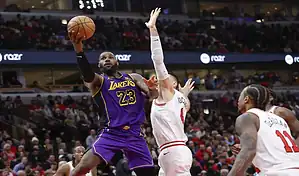 Los Angeles Lakers player driving to the basket against Chicago Bulls defenders during an NBA game.