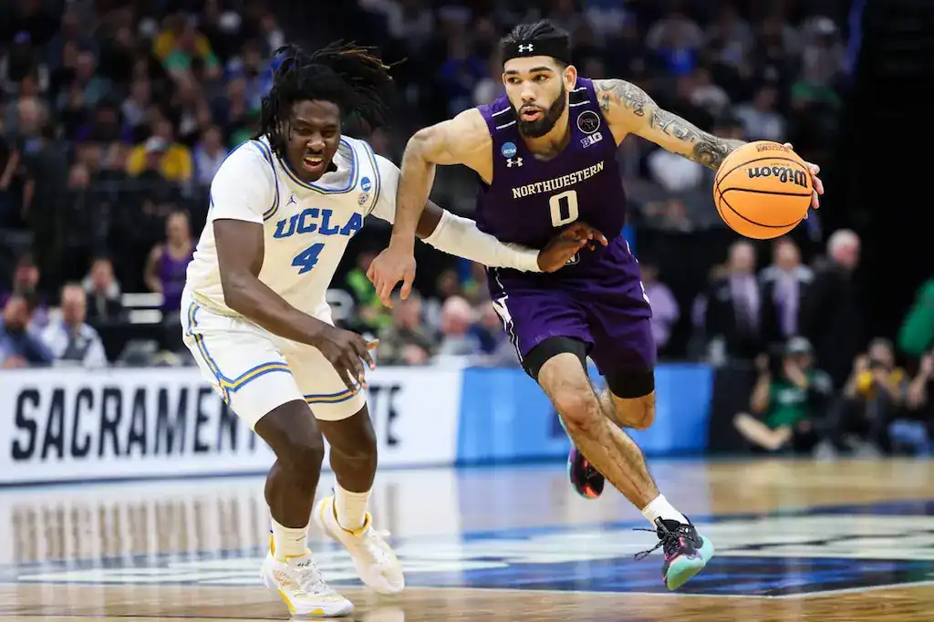 Northwestern basketball player driving past UCLA defender during an NCAA tournament game.