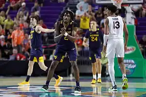 West Virginia Mountaineers player clapping hands during a college basketball game against Virginia Tech.