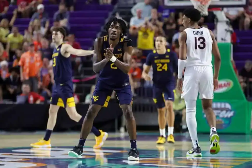 West Virginia Mountaineers player clapping hands during a college basketball game against Virginia Tech.