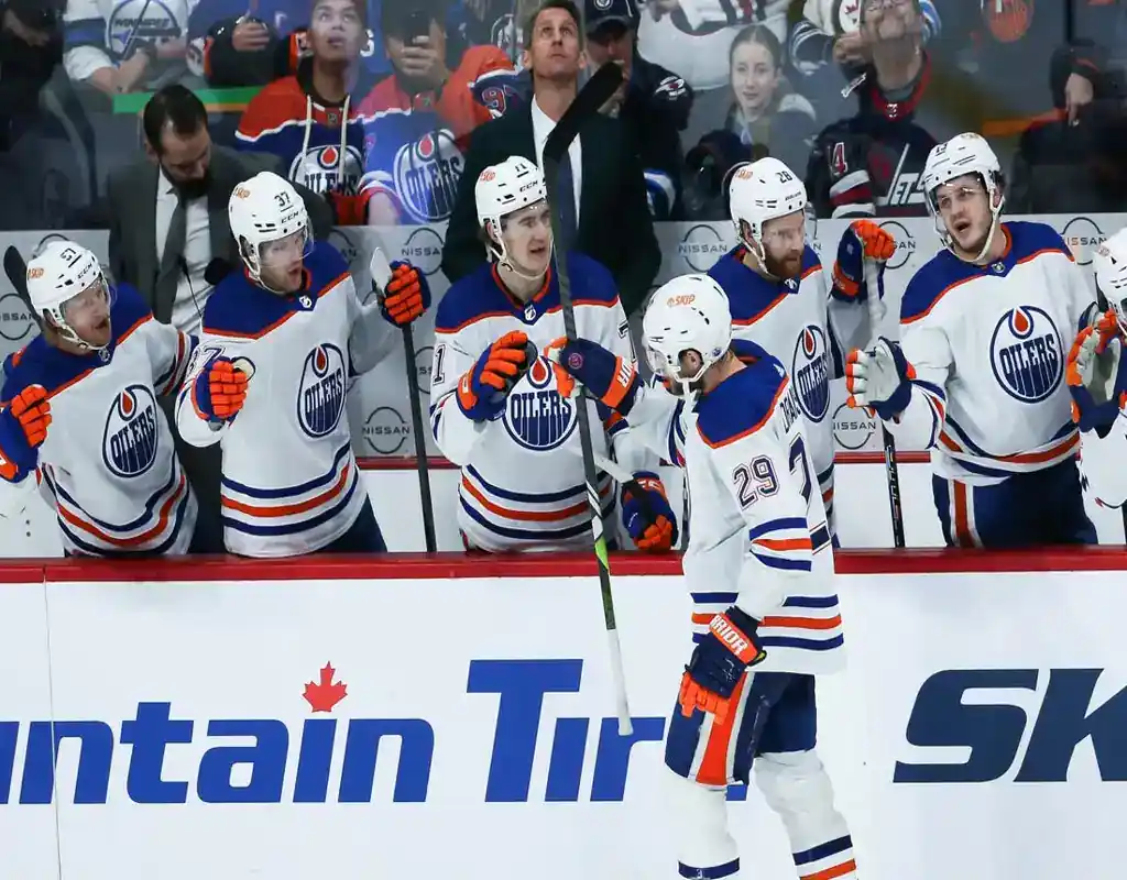 Edmonton Oilers players celebrating near the bench during a hockey game against the Carolina Hurricanes