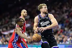 Philadelphia 76ers defender reaching in to steal the basketball from a Sacramento Kings player driving in the lane during NBA action.