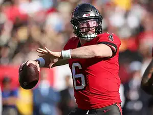Tampa Bay Buccaneers quarterback winding up to throw a pass during an NFL game, wearing a red jersey and black helmet.