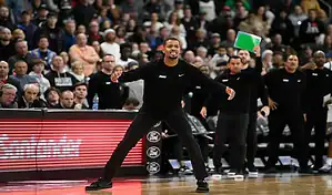 Providence Friars coach directing players from the sideline during a college basketball game.