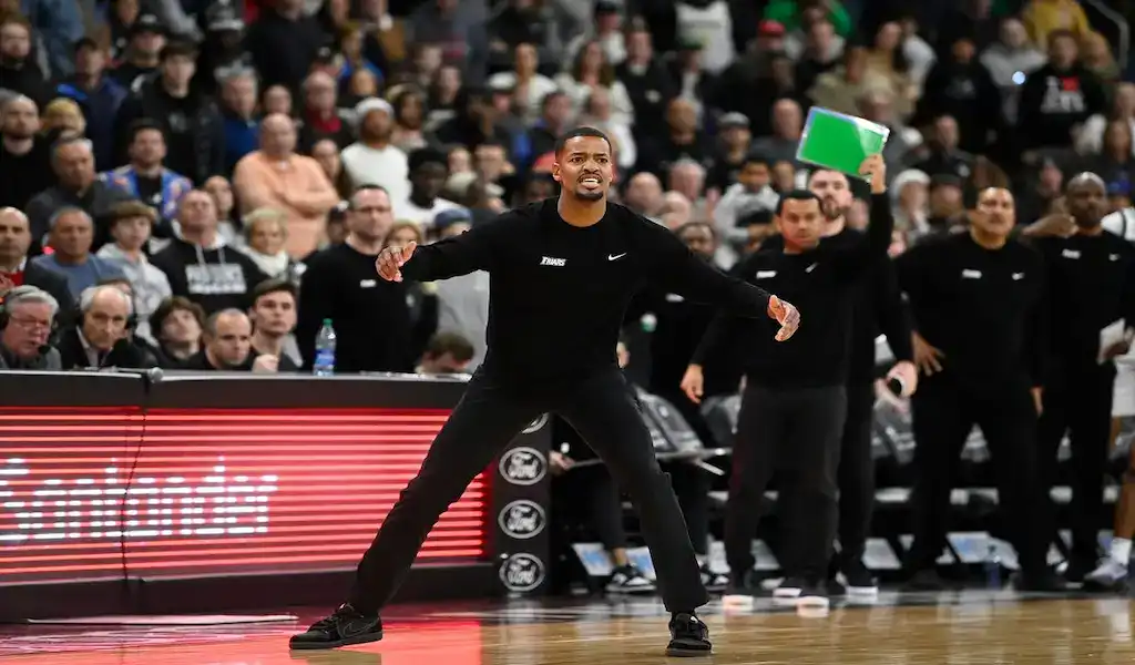 Providence Friars coach directing players from the sideline during a college basketball game.
