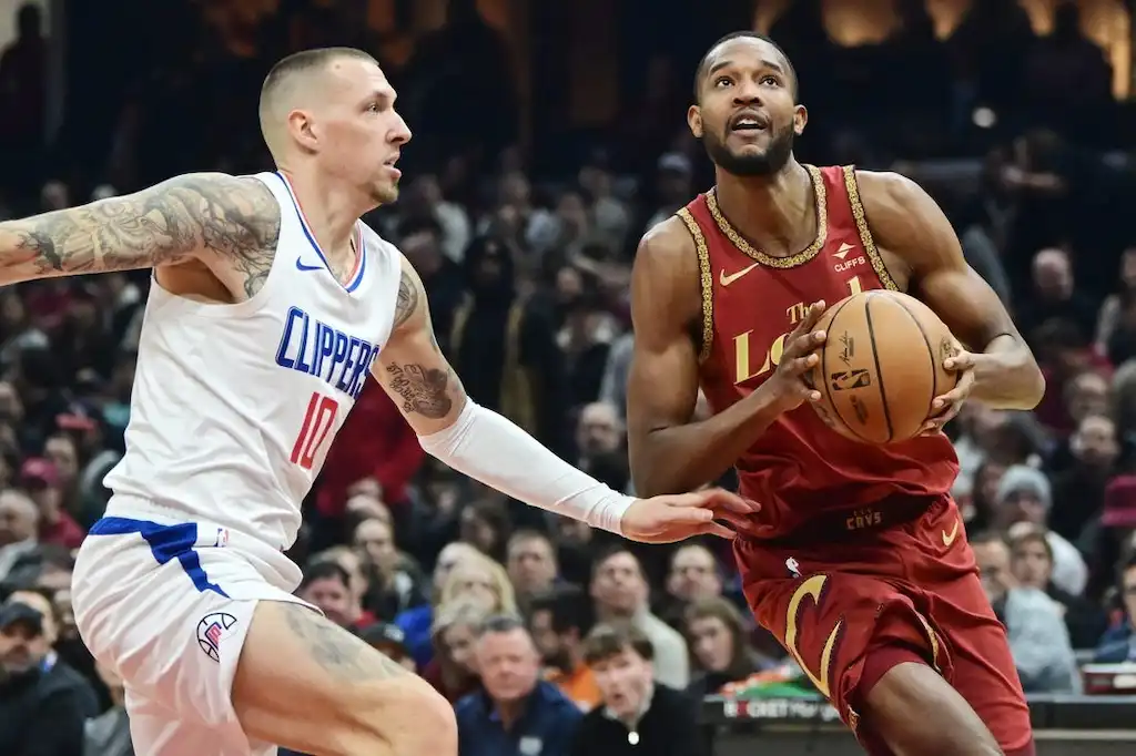A Cleveland Cavaliers player drives to the basket while being closely defended by a player.