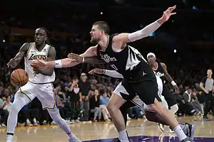 Los Angeles Lakers guard controls the ball as a Los Angeles Clippers defender reaches out to contest.