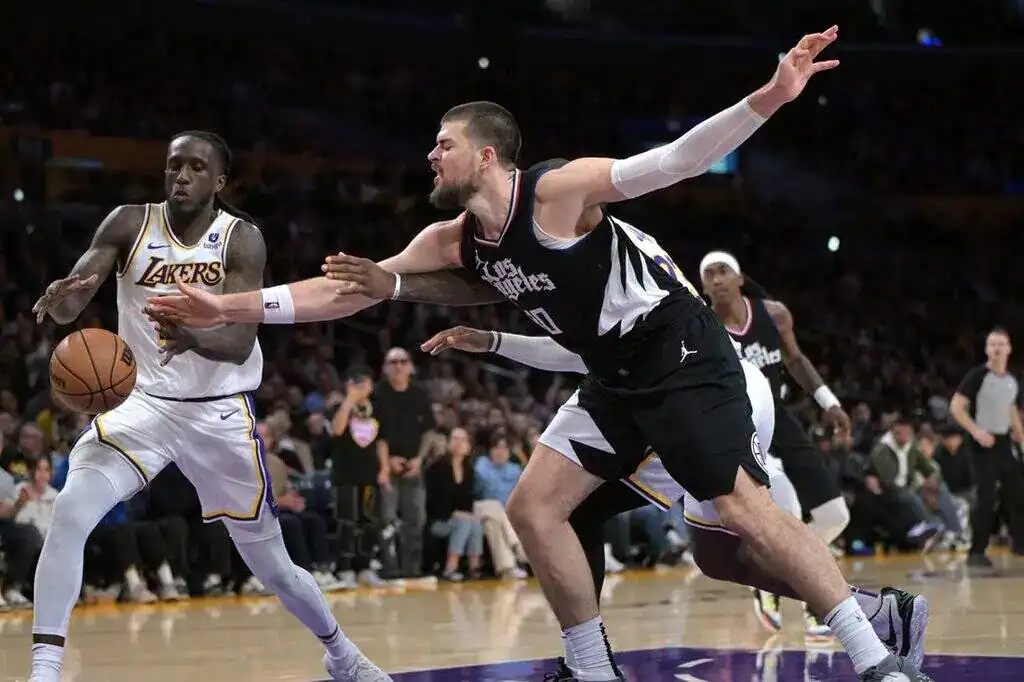 Los Angeles Lakers guard controls the ball as a Los Angeles Clippers defender reaches out to contest.