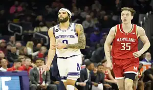Northwestern Wildcats player dribbling past Maryland defender during a college basketball game