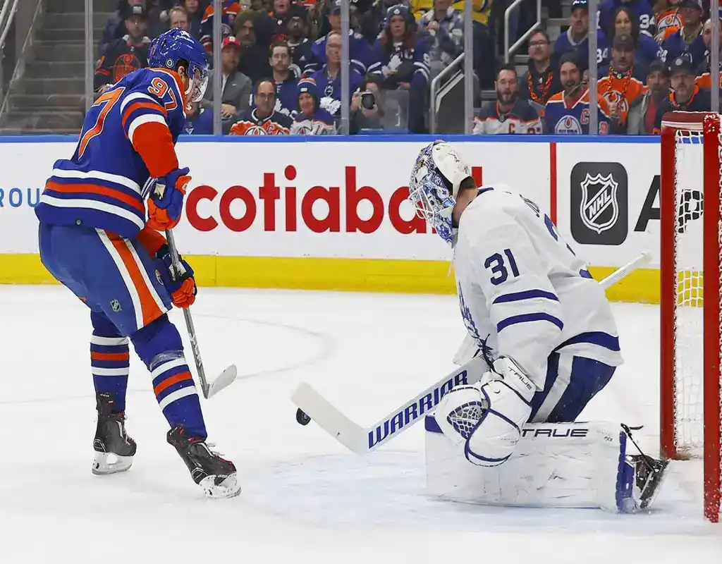 Edmonton Oilers forward attempts to score against Toronto Maple Leafs goalie during NHL game