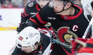 Ottawa Senators captain battles for position against a Calgary Flames player during an NHL game.