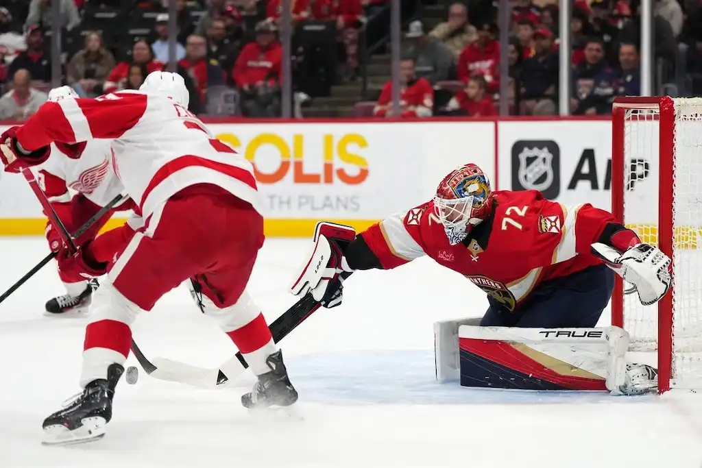 A Florida Panthers goalie stretches out to make a glove save against a Detroit Red Wings player