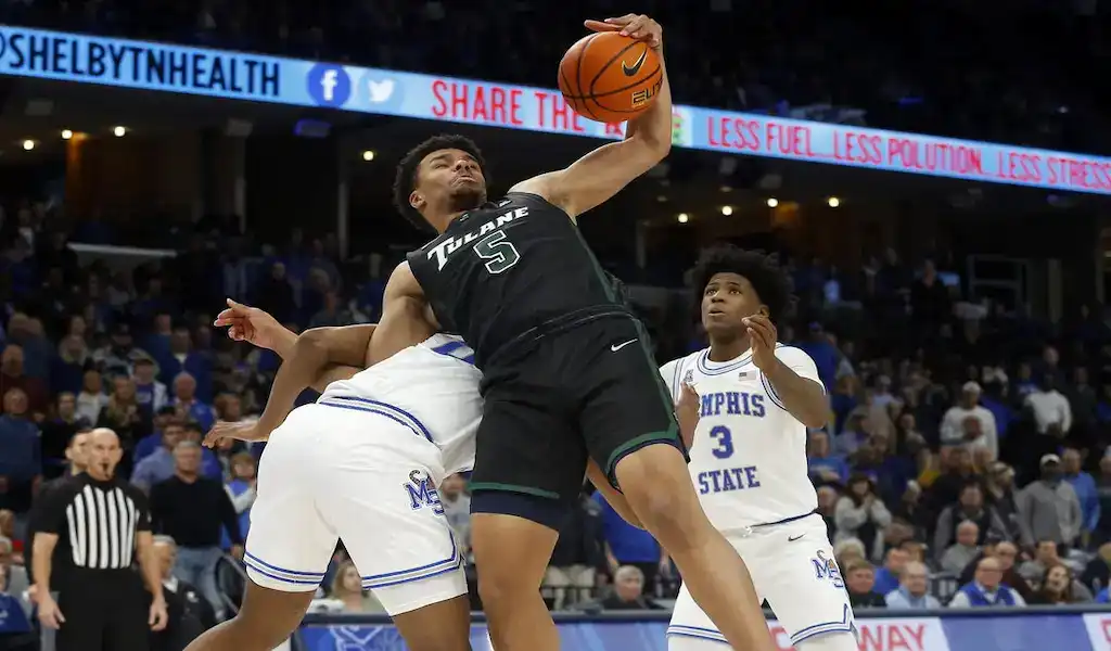 A basketball player in a black jersey leaps to grab a rebound against players in white Memphis State jerseys. The scene is intense and action-packed.