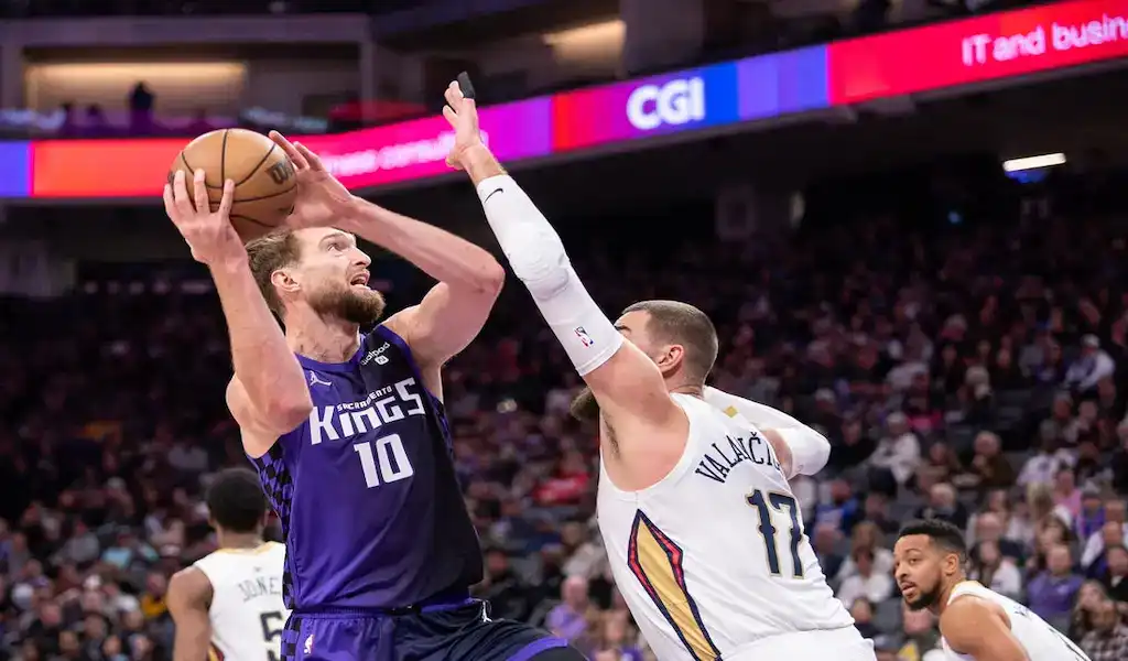 Sacramento Kings player driving to the basket against the Charlotte Hornets defense in an NBA game.