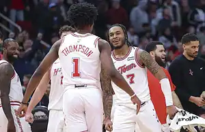 Houston Rockets players smile and celebrate together on the court after a play.